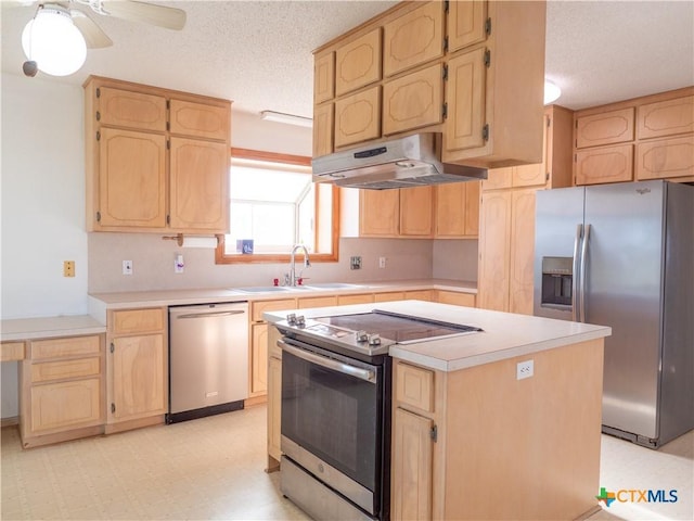 kitchen with ceiling fan, stainless steel appliances, sink, a textured ceiling, and a center island