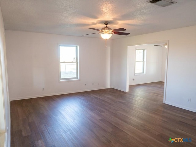 empty room with a textured ceiling, dark hardwood / wood-style flooring, and a healthy amount of sunlight