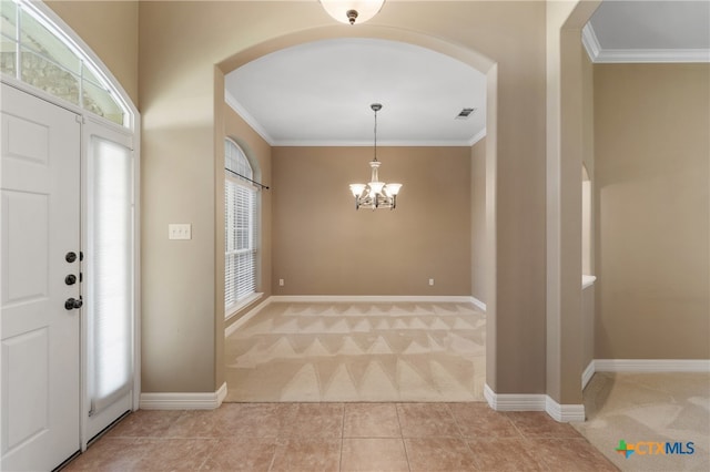 tiled entryway with ornamental molding, a notable chandelier, and a healthy amount of sunlight