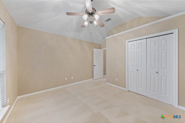 unfurnished bedroom with a closet, vaulted ceiling, light carpet, and ceiling fan