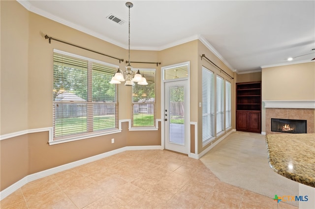 entryway featuring ornamental molding, ceiling fan with notable chandelier, a tiled fireplace, and light tile patterned floors