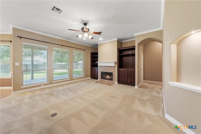 unfurnished living room featuring crown molding, light colored carpet, ceiling fan, and a fireplace