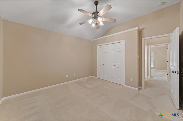 unfurnished bedroom featuring light colored carpet, ceiling fan, vaulted ceiling, and a closet