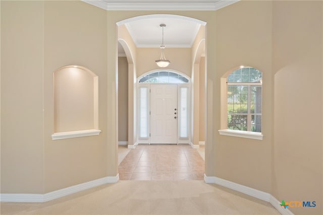 entryway featuring a high ceiling, light tile patterned floors, and crown molding