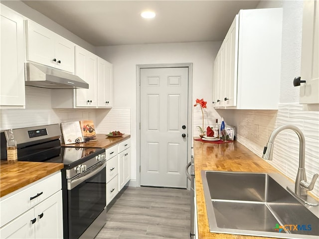 kitchen with butcher block countertops, tasteful backsplash, white cabinetry, sink, and electric range