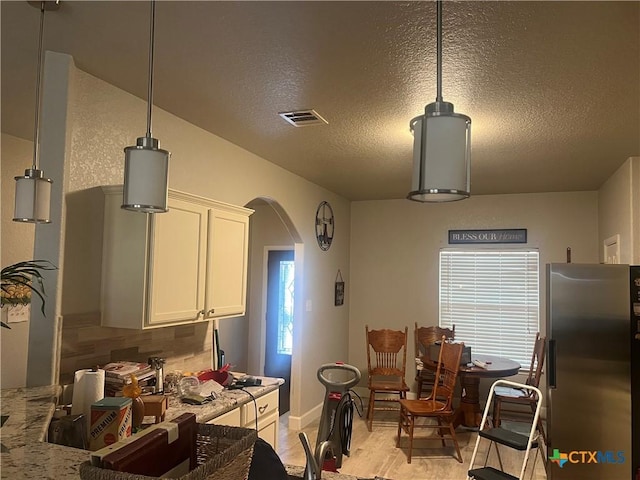 355 Primrose Way, New Braunfels, TX 78132 - kitchen with freestanding refrigerator, arched walkways, white cabinets, a textured ceiling, and tasteful backsplash