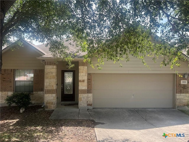 355 Primrose Way, New Braunfels, TX 78132 - view of front facade featuring concrete driveway, an attached garage, and stone siding