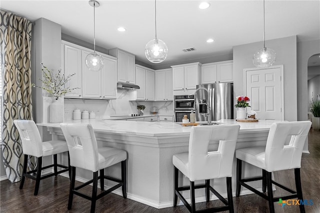 kitchen with dark hardwood / wood-style flooring, hanging light fixtures, a breakfast bar, and stainless steel appliances