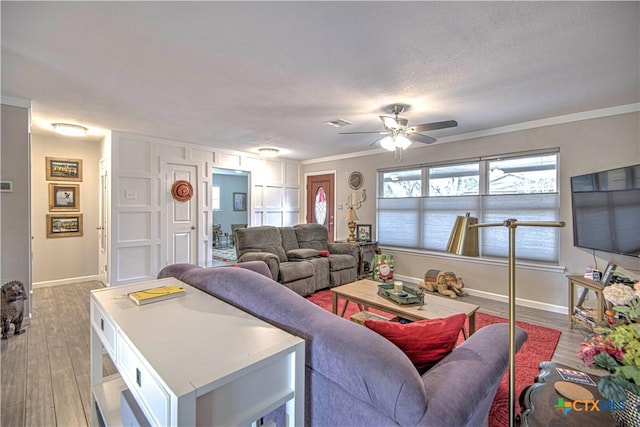 living room featuring ceiling fan, crown molding, light hardwood / wood-style floors, and a textured ceiling