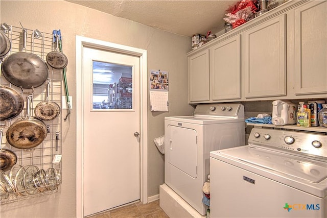 laundry room featuring washing machine and dryer, cabinets, a textured ceiling, and light tile patterned flooring