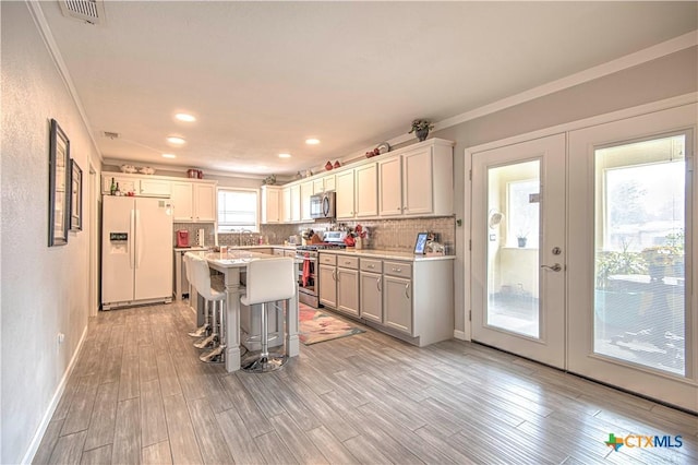 kitchen featuring french doors, a breakfast bar, a center island, light wood-type flooring, and stainless steel appliances