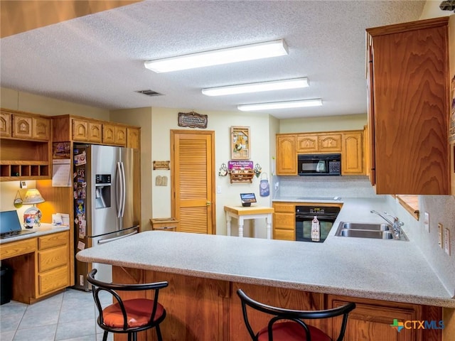 kitchen with black appliances, a kitchen bar, kitchen peninsula, and sink