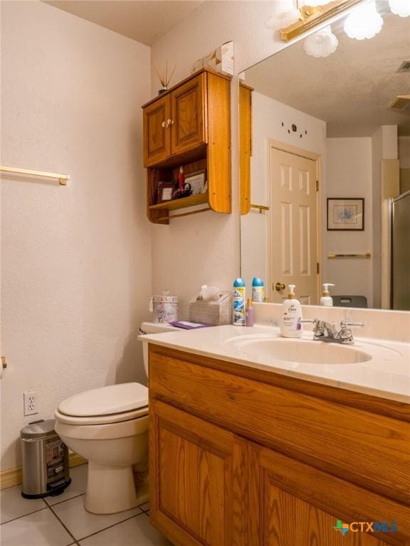 bathroom featuring tile patterned floors, vanity, toilet, and a shower with door