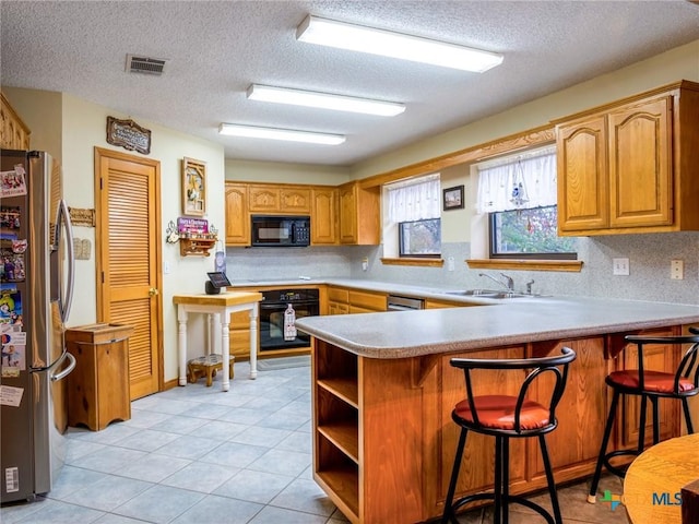 kitchen featuring kitchen peninsula, sink, black appliances, and a textured ceiling