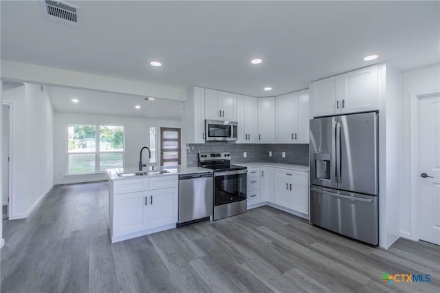 575 Live Oak Dr, Bertram, TX 78605 - kitchen with appliances with stainless steel finishes, a peninsula, wood finished floors, white cabinetry, and light countertops