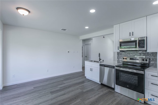 575 Live Oak Dr, Bertram, TX 78605 - kitchen featuring appliances with stainless steel finishes, white cabinets, decorative backsplash, recessed lighting, and wood finished floors