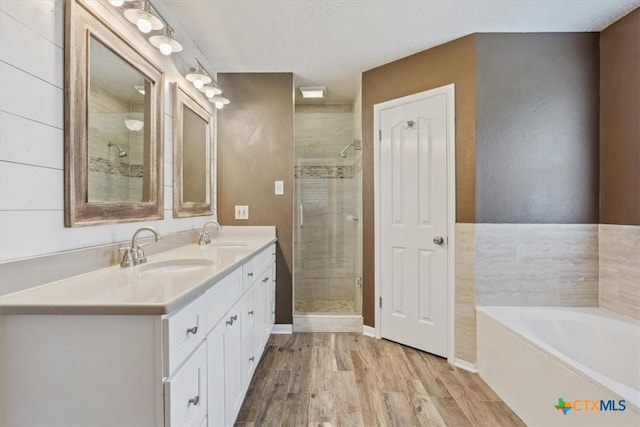 bathroom featuring a bath, a sink, a stall shower, and wood finished floors