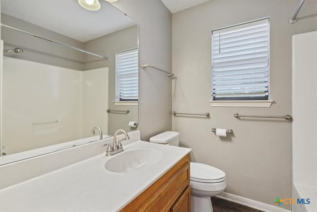 bathroom featuring baseboards, toilet, vanity, and walk in shower