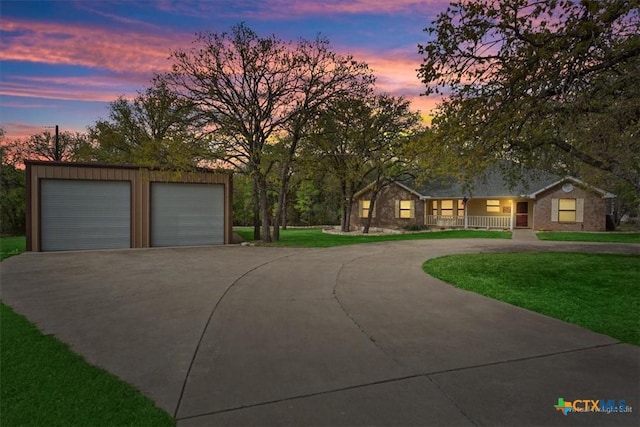 view of front of home with a front lawn, covered porch, an outdoor structure, and curved driveway
