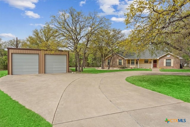 view of front of house featuring a front yard, a detached garage, a porch, and an outbuilding