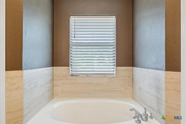 bathroom with a textured wall and a bath