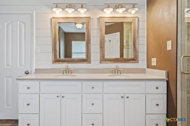 bathroom with double vanity, a sink, and a shower with shower door