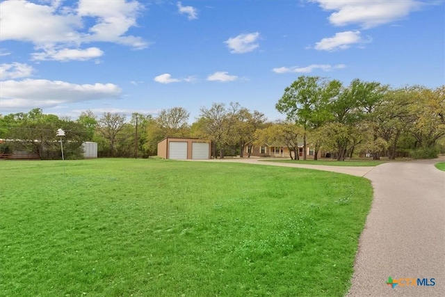 view of yard featuring driveway, an outbuilding, and a detached garage