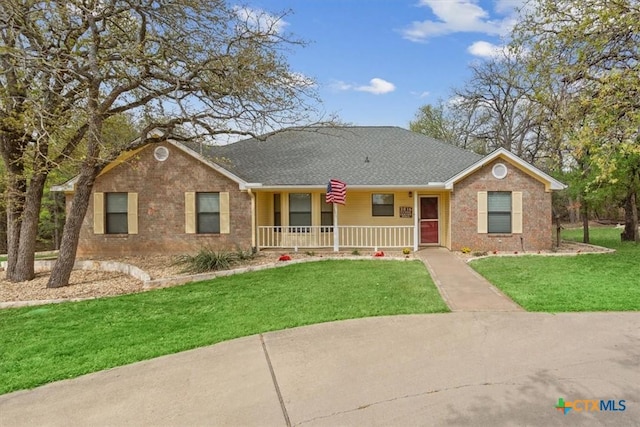 ranch-style home with a front yard, brick siding, a porch, and roof with shingles