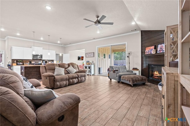 2635 Bolzano Trl, Temple, TX 76502 - living area featuring a ceiling fan, a fireplace, crown molding, recessed lighting, and light wood-type flooring