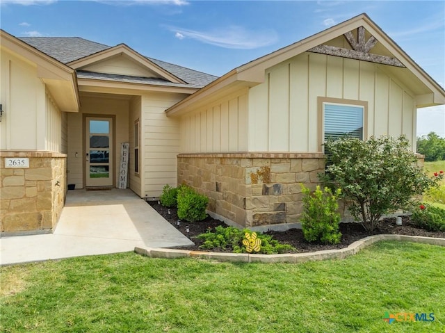 2635 Bolzano Trl, Temple, TX 76502 - entrance to property featuring board and batten siding, a shingled roof, a yard, and stone siding