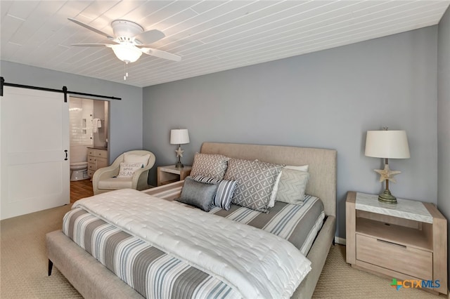 carpeted bedroom featuring connected bathroom, a barn door, and ceiling fan