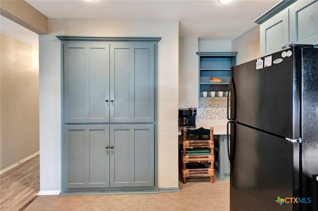 kitchen featuring light wood-type flooring and black fridge