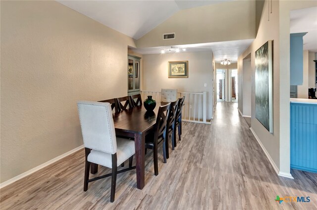 dining room with light wood-type flooring and vaulted ceiling