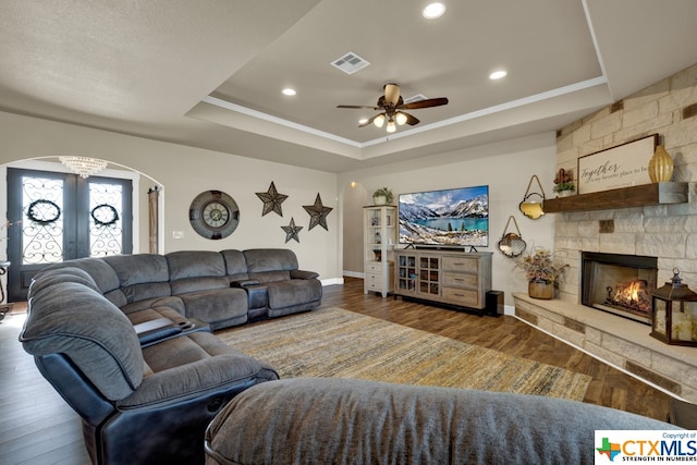 living room with dark wood-type flooring, a tray ceiling, and ceiling fan