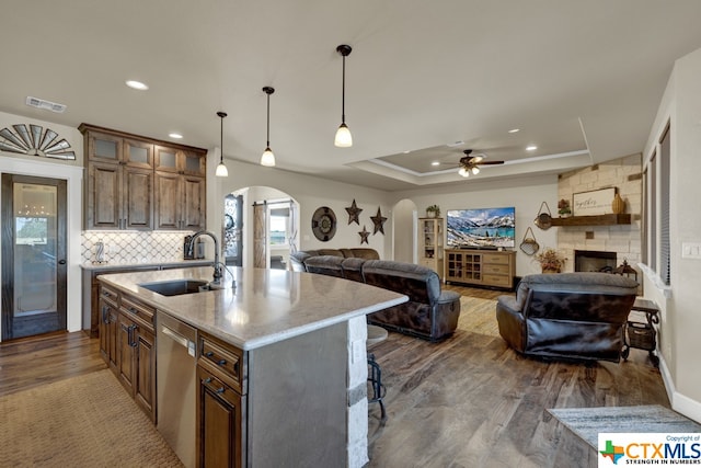 kitchen with stainless steel dishwasher, hardwood / wood-style flooring, a center island with sink, and sink