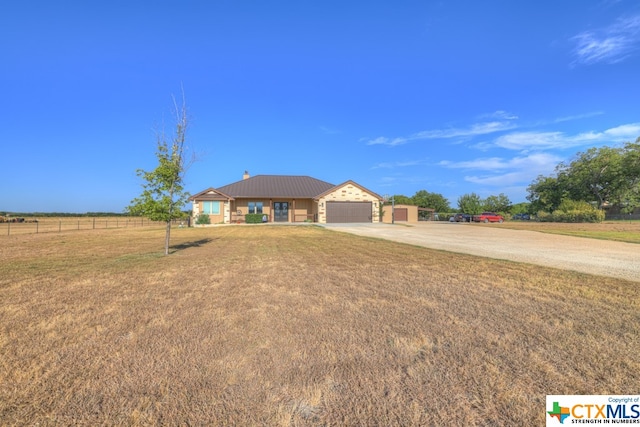 ranch-style home featuring a garage, a rural view, and a front yard