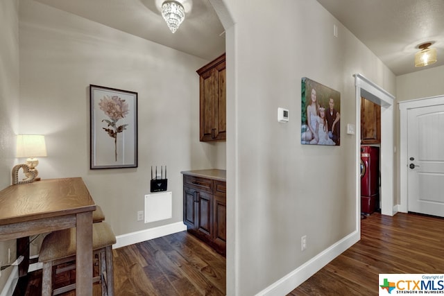 hall with dark wood-type flooring and washer / dryer