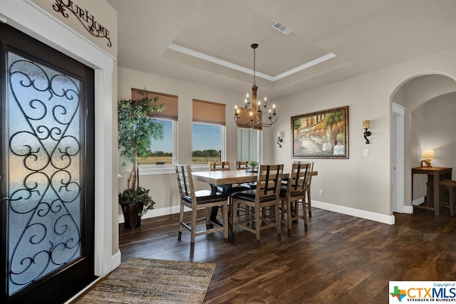 dining space featuring dark wood-type flooring, a notable chandelier, and a tray ceiling