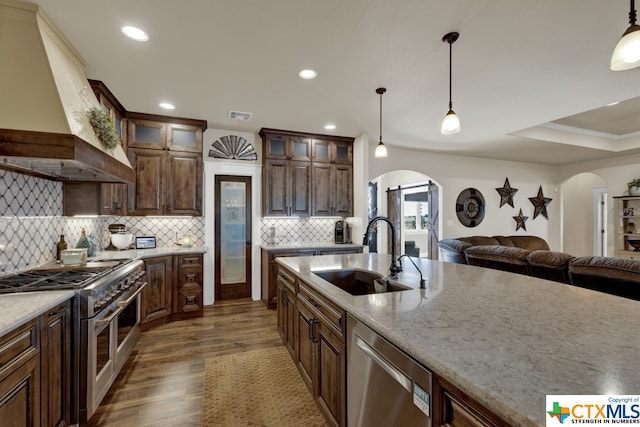 kitchen with premium range hood, backsplash, appliances with stainless steel finishes, dark hardwood / wood-style floors, and sink