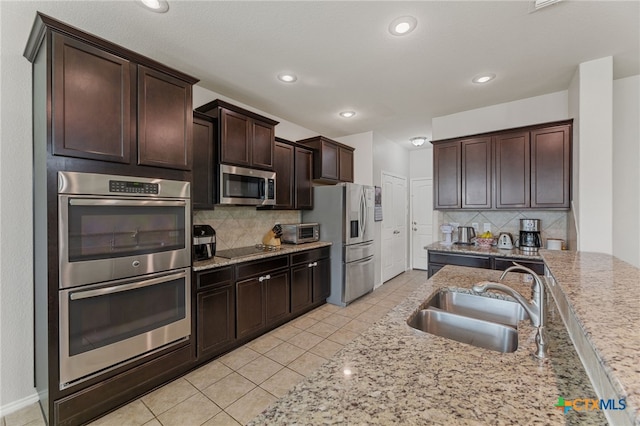 kitchen featuring decorative backsplash, sink, light stone counters, and stainless steel appliances