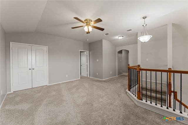 carpeted spare room featuring ceiling fan and vaulted ceiling