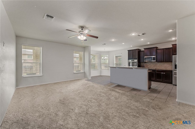 kitchen featuring stainless steel appliances, a center island with sink, a healthy amount of sunlight, and decorative backsplash