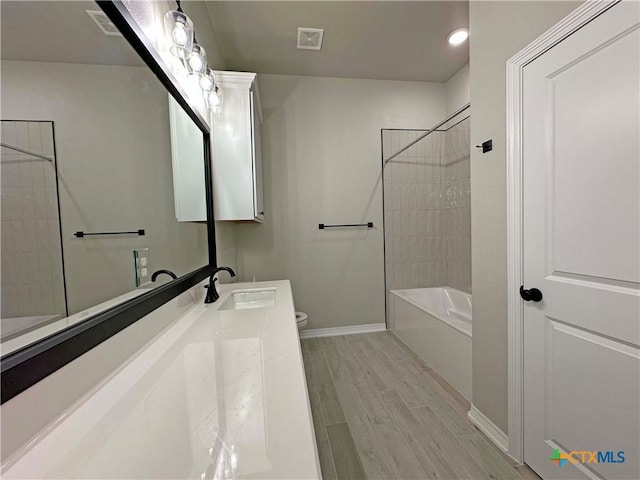 full bathroom with tiled shower / bath combo, wood-type flooring, vanity, and toilet