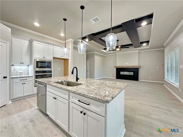 kitchen featuring sink, white cabinetry, stainless steel appliances, an island with sink, and decorative light fixtures