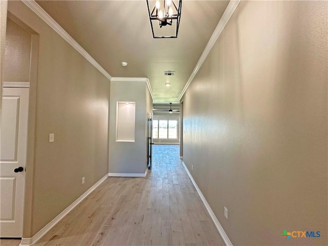 hall with a chandelier, ornamental molding, and light hardwood / wood-style flooring