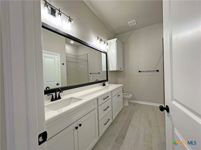 bathroom featuring wood-type flooring, toilet, vanity, and a shower