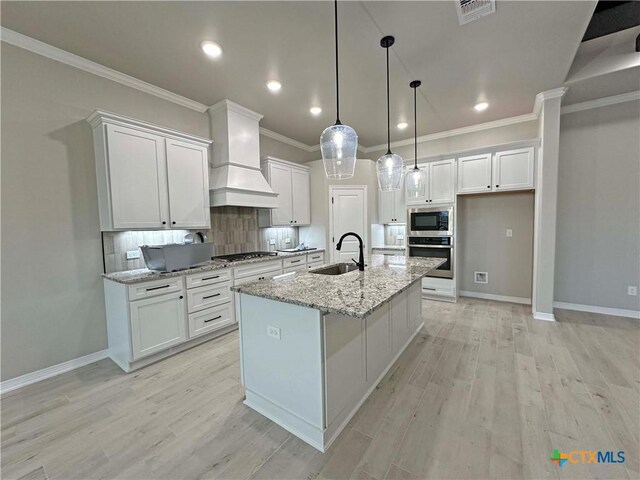 kitchen featuring white cabinets, sink, ceiling fan with notable chandelier, and an island with sink