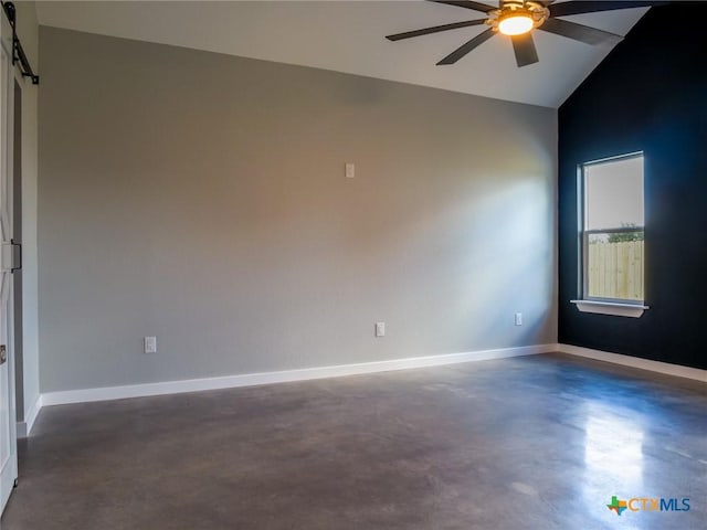 empty room featuring vaulted ceiling, a barn door, and ceiling fan