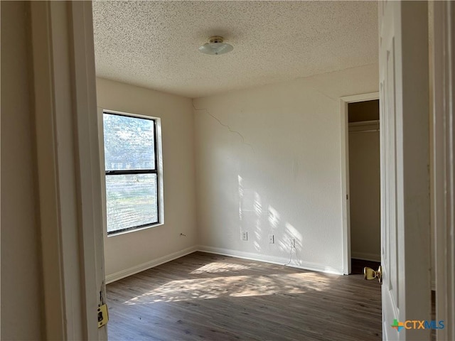 unfurnished room with a textured ceiling and dark hardwood / wood-style floors