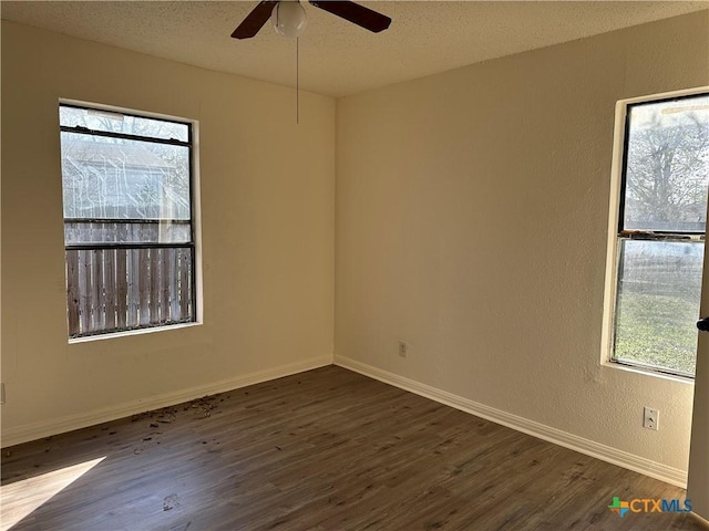 spare room featuring a wealth of natural light, ceiling fan, dark wood-type flooring, and a textured ceiling